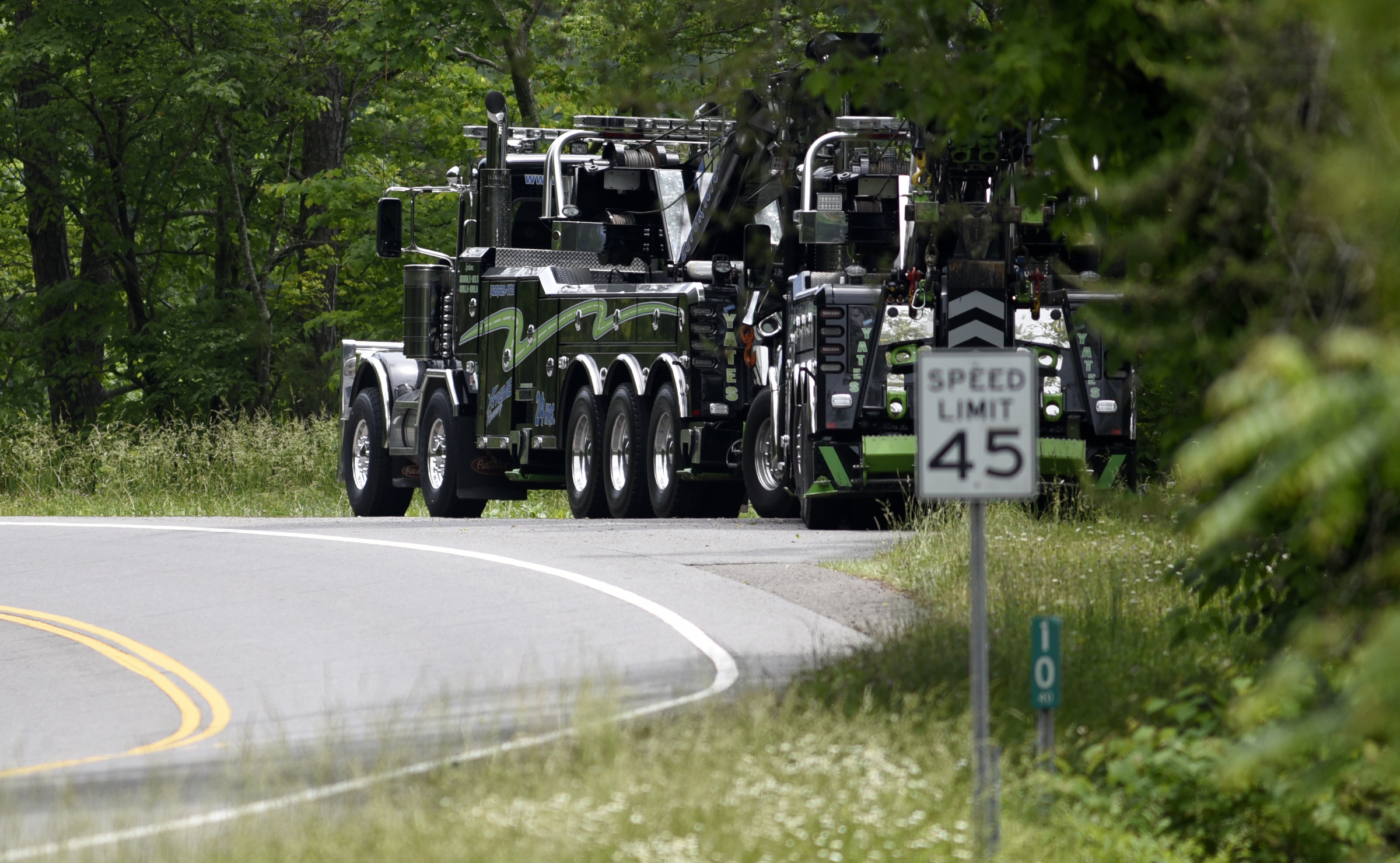 A pair of tow trucks sit along Highway 64 in Polk County waiting to help remove a overturned tanker truck on Thursday, May 17, 2018, in Benton, Tenn.