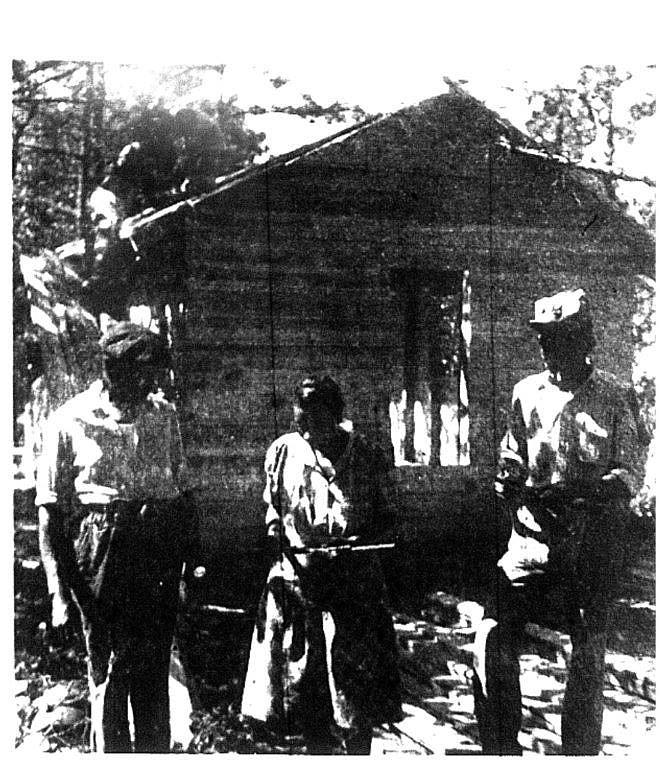 Butler and Pressie Frazier, on the left, leaders in the resettlement project of Tyner black families, talk with Lewis Johnson in front of his temporary home while students work on the roof.