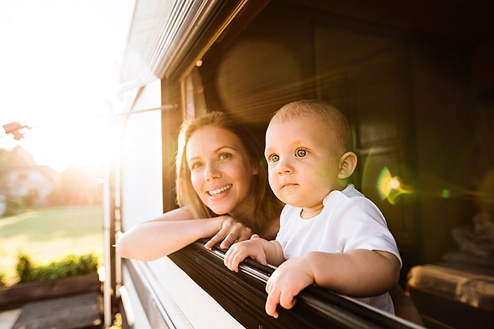 Beautiful young mother and her baby son in a camper van on a summer day