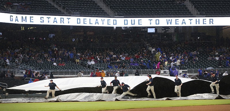 Members of the Atlanta Braves grounds crew rush to cover the infield during a rain shower before the Braves' baseball game against the Chicago Cubs on Thursday, May 17, 2018, in Atlanta. (AP Photo/John Bazemore)