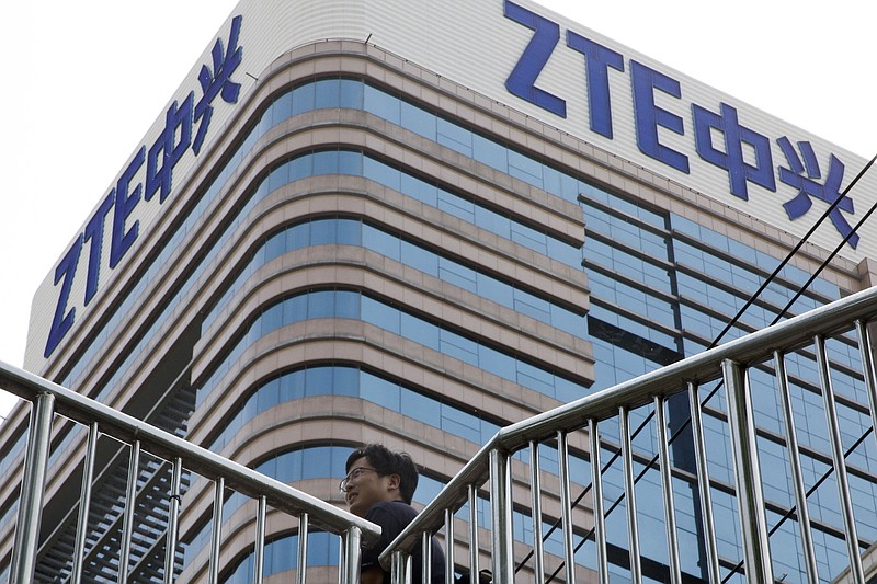 In this photo taken May 8, 2018, a man walks past a building with the ZTE logos in Beijing. As Chinese officials prepare to hold talks with their counterpart in Washington the two countries are reportedly attempting a swap: Relief for ZTE in return for Beijing dropping plans to impose tariffs on U.S. farm products. (AP Photo/Ng Han Guan)