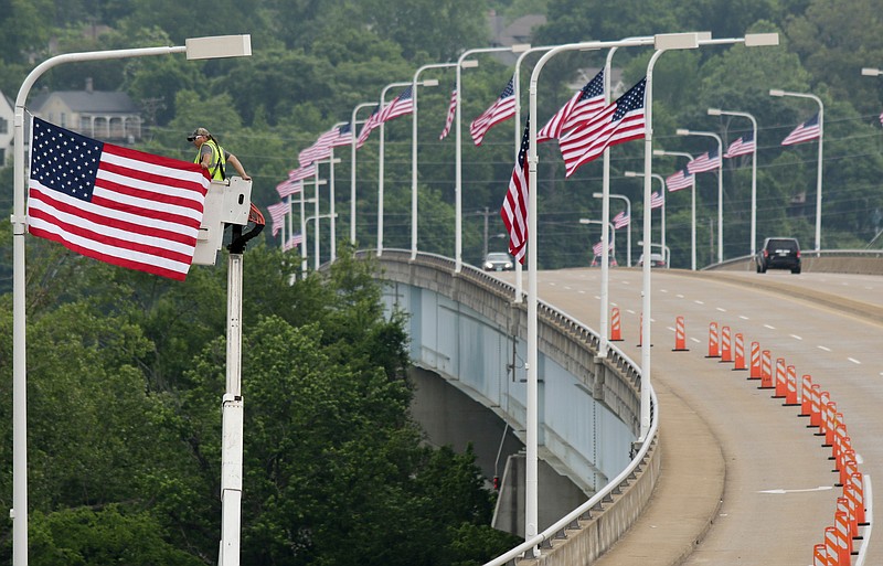 Eddie Poe with the city's public works department raises an American flag on Veterans Bridge during the Veterans Bridge Flag Raising Ceremony on Friday, May 18, 2018, in Chattanooga, Tenn. The annual installation of new American flags on the bridge ahead of Armed Forces Day honors the city's veterans.