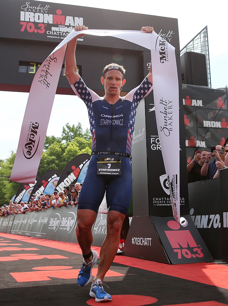 Andrew Starykowicz raises the banner above his head as he finishes in first place during Ironman 70.3 Chattanooga Sunday, May 20, 2018 in Chattanooga, Tenn. Starykowicz finished with a time of 3:46:28.