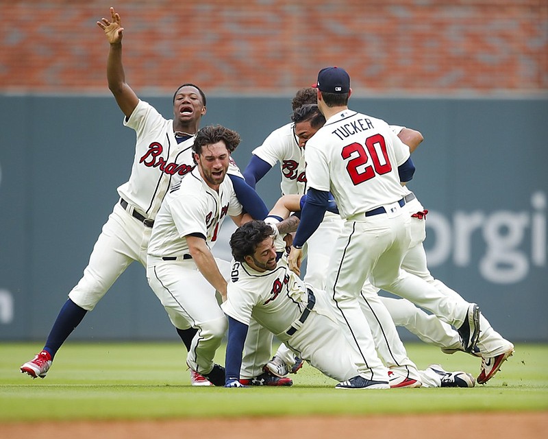 Atlanta Braves shortstop Dansby Swanson is tackled by his teammates after hitting a two-run single with two outs in the ninth inning of Sunday's home game against the Miami Marlins. Swanson's hit completed a six-run ninth inning as the Braves rallied to win 10-9.