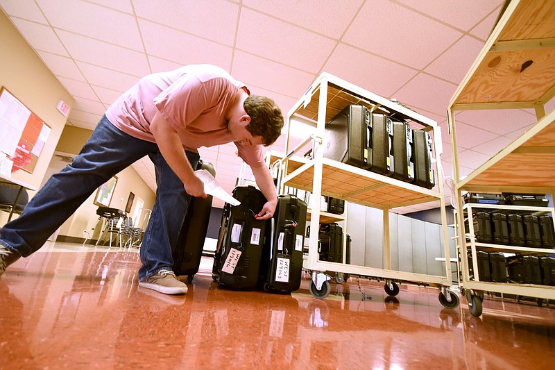 Inside the Catoosa County Elections central offices in Ringgold Monday morning, Ty Raley checks a tag number before transporting voting machines to the Westside and Lakeview precincts.