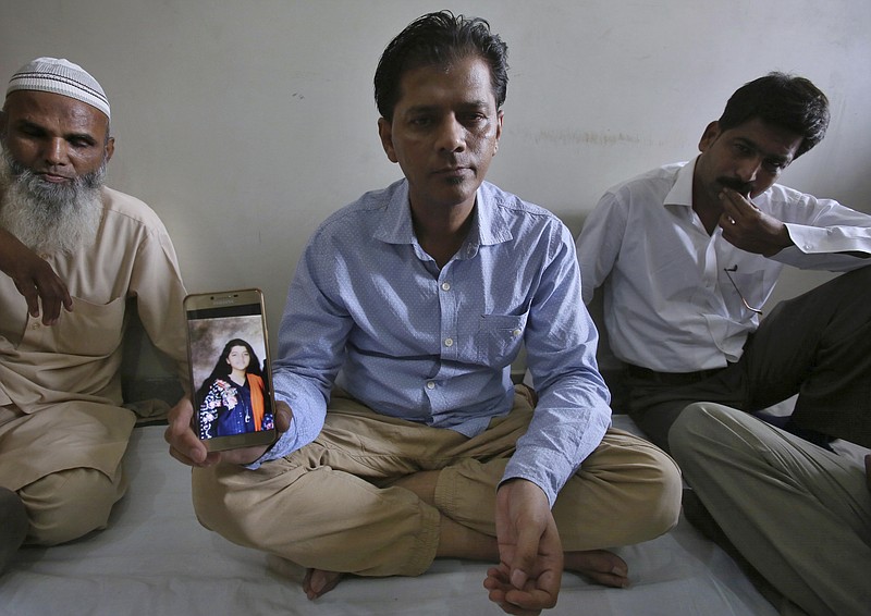 Abdul Aziz Sheikh, center, father of Sabika Sheikh, a victim of a shooting at a Texas high school, shows a picture of his daughter in Karachi, Pakistan, Saturday, May 19, 2018. The Pakistani foreign exchange student is among those killed in the shooting, according to a leader at a program for foreign exchange students and the Pakistani Embassy in Washington, D.C. Megan Lysaght, manager of the Kennedy-Lugar Youth Exchange & Study Abroad program (YES), sent a letter to students in the program confirming that Sabika Sheikh was killed in the shooting. (AP Photo/Fareed Khan)

