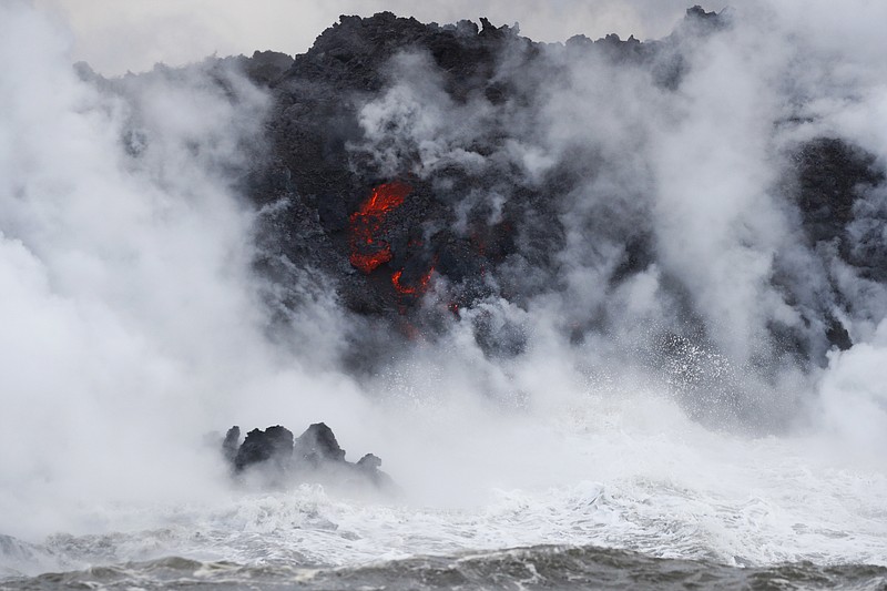 Steam rises as lava flows into the ocean near Pahoa, Hawaii, Sunday, May 20, 2018. Kilauea volcano that is oozing, spewing and exploding on Hawaii's Big Island has gotten more hazardous in recent days, with rivers of molten rock pouring into the ocean Sunday and flying lava causing the first major injury. (AP Photo/Jae C. Hong)