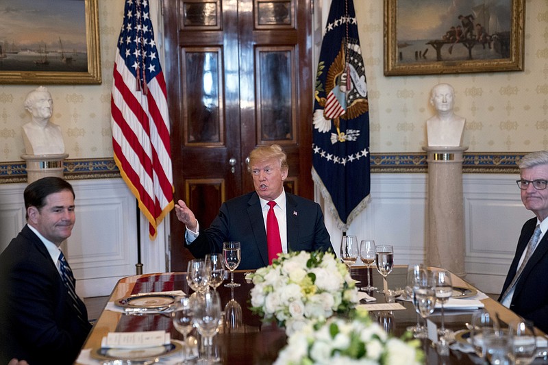 President Donald Trump, center, accompanied by Arizona Gov. Doug Ducey, left, and Mississippi Gov. Phil Bryant, right, speaks during a meeting with a group of governors in the Blue Room of the White House in Washington, Monday, May 21, 2018, to discuss border security and restoring safe communities. (AP Photo/Andrew Harnik)