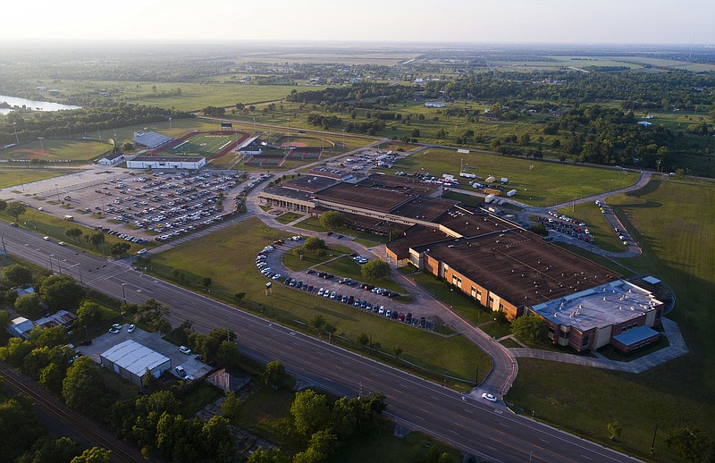 In this Friday, May 18, 2018, file photo, cars remain in the parking lot where they were left as the sun sets on Santa Fe High School, the scene of a deadly shooting earlier in the day with multiple fatalities, mostly students, in Santa Fe, Texas. If you want to know where mass school shootings are most likely to occur, look no farther than small-town and suburban America. (Mark Mulligan/Houston Chronicle via AP, File)