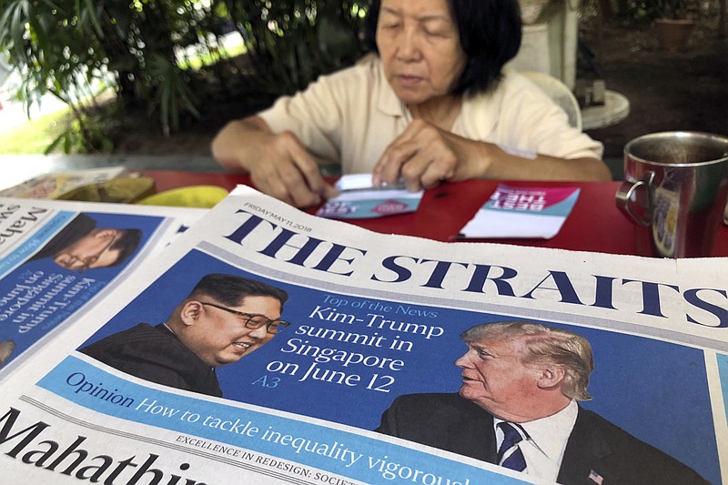 FILE - In this May 11, 2018, file photo, a news vendor counts her money near a stack of newspapers with a photo of U.S. President Donald Trump, right, and North Korea's leader Kim Jong Un on its front page in Singapore.