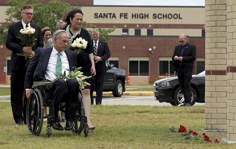 Gov. Greg Abbott, his wife, Cecilia, Lt. Gov. Dan Patrick, along with Sen. Larry Taylor and Rep. Greg Bonnen prepare to place flowers Sunday, May 20, 2018, at Santa Fe High School where a gunman opened fire Friday killing 10 people, in Santa Fe, Texas. (Jennifer Reynolds/The Galveston County Daily News via AP)