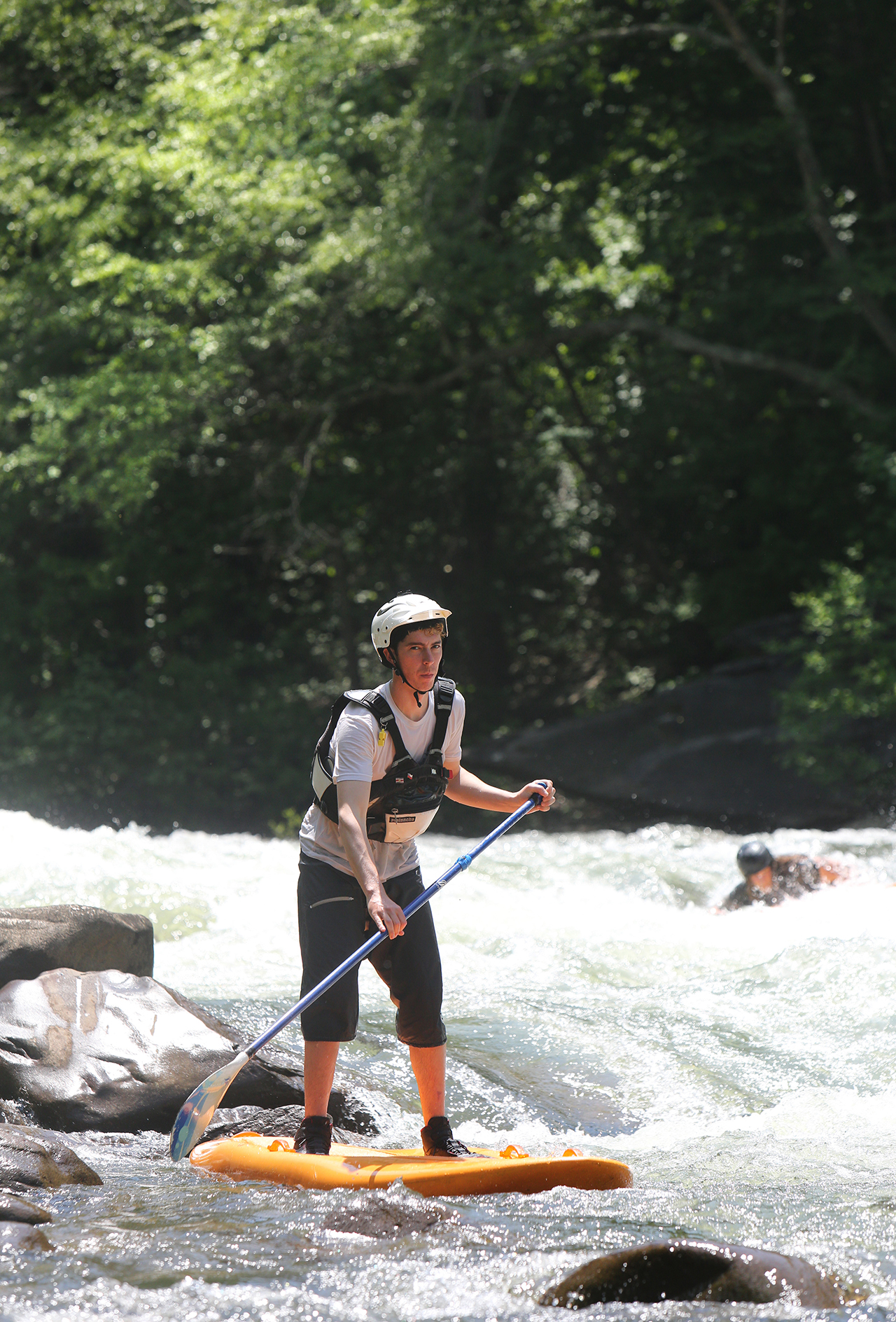 Chris Storgion, 24, balances on his standup paddle board as Alex Storgion, 26, attempts to get back up on his after falling off in the background on the Ocoee River in Benton, Tenn., Monday, May 14, 2018.