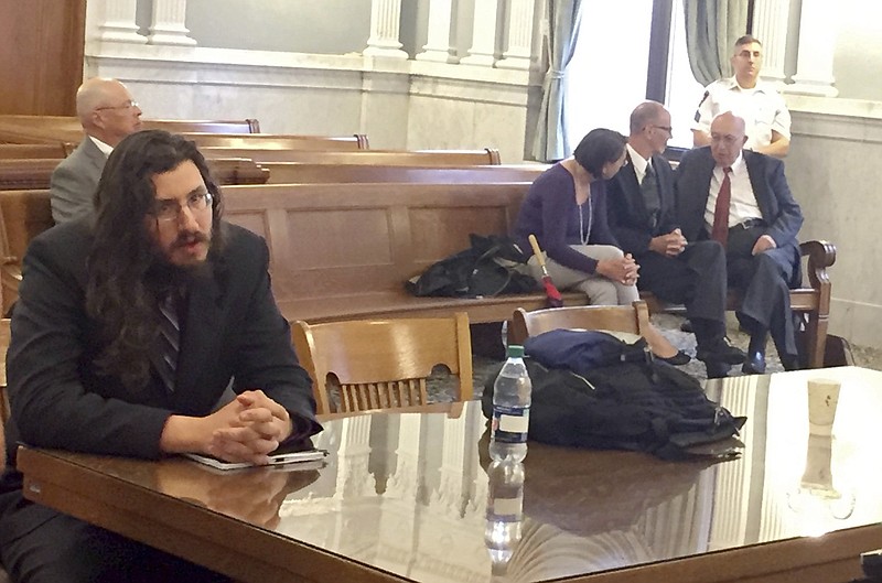 Michael Rotondo, left, sits during an eviction proceeding in Syracuse, N.Y., brought by his parents, Mark and Christina, of Camillus. The two parents confer with their lawyer, Anthony Adorante, in the court gallery behind. Rotondo told the judge Tuesday, May 22, 2018, he knows his parents want him out of their Camillus home, near Syracuse. But he argued he's entitled to six months more time. (Douglass Dowty /The Syracuse Newspapers via AP)