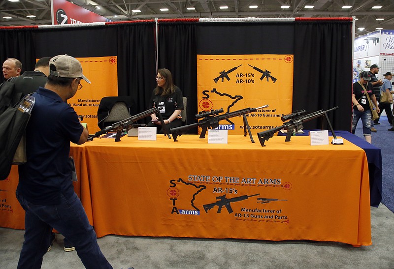 In this May 4, 2018, file photo, attendees walk by a display of AR-15's and AR-10's at the National Rifle Association convention in Dallas. Gun-control advocates push for tougher laws, including universal background checks to prohibiting the sale and possession of AR-style long guns. NRA and many Republican leaders insist the root of the problem is not guns but a range of issues such as mental health, school security, video games and excessive prescriptions of attention-deficit disorder drugs such as Ritalin. (AP Photo/Sue Ogrocki, File)