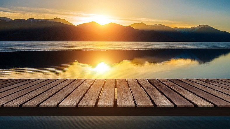 Wooden bridge on the lake with a reflection of sunset on the snow mountain (Getty Images)