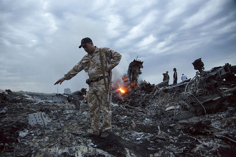 FILE - In this July 17, 2014. file photo, people walk amongst the debris at the crash site of a passenger plane near the village of Grabovo, Ukraine. An international team of investigators says that detailed analysis of video images has established that the Buk missile that brought down Malaysia Airlines Flight 17 nearly four years ago came from a Russia-based military unit. Wilbert Paulissen of the Dutch National Police said Thursday, May 24, 2018 that the missile was from the Russian military’s 53rd anti-aircraft missile brigade based in the Russian city of Kursk. (AP Photo/Dmitry Lovetsky, File)