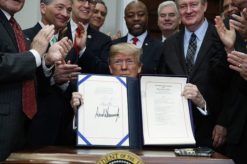 President Donald Trump shows off the "Economic Growth, Regulatory Relief, and Consumer Protection Act," in the Roosevelt Room of the White House, Thursday, May 24, 2018, in Washington.   (AP Photo/Evan Vucci)