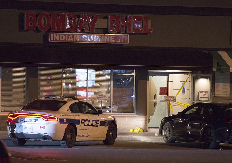 Police stand outside the Bombay Bhel restaurant in Mississauga, Canada Friday May 25, 2018. Canadian police say an explosion set off deliberately in a restaurant has wounded a number of people. (Doug Ives/The Canadian Press via AP)