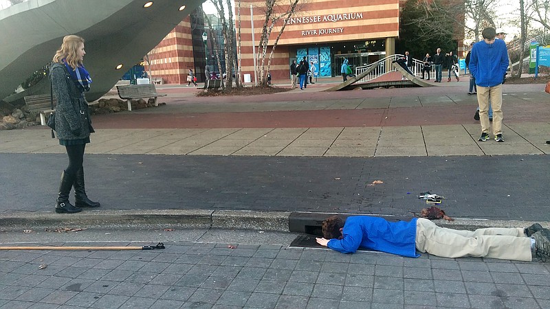 Tim Martin, a staff member at the Tennessee Aquarium retrieves Cara DeLoach's phone from a stormwater drain.