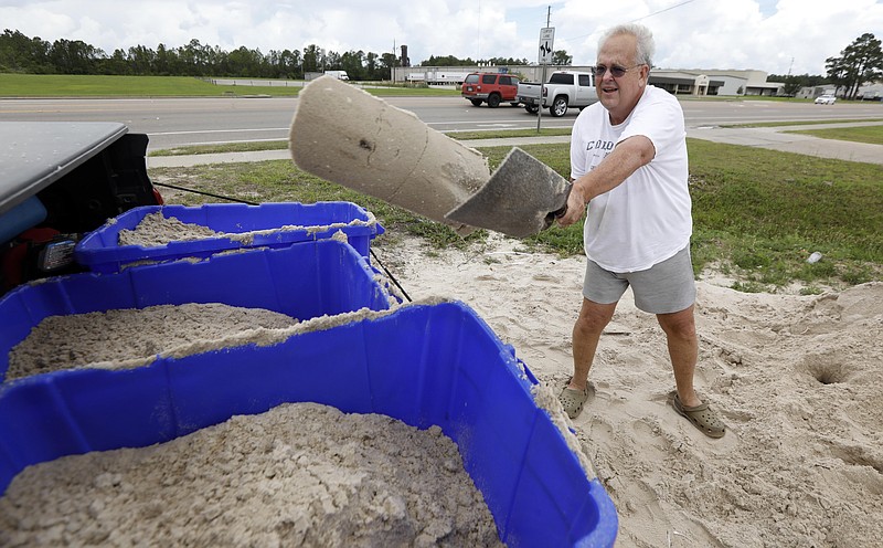 George Estes tosses sand into storage tubs at a Harrison County Road Department sand bagging location, that he will take back to his law office in downtown Gulfport, Miss., and will enlist help to fill bags that he will place by his office doors and plate glass window, while preparing for Subtropical Storm Alberto to make its way through the Gulf of Mexico in Gulfport, Miss., Saturday, May 26, 2018. The slow moving storm is threatening to bring heavy rainfall, storm surges, high wind and flash flooding this holiday weekend. (AP Photo/Rogelio V. Solis)