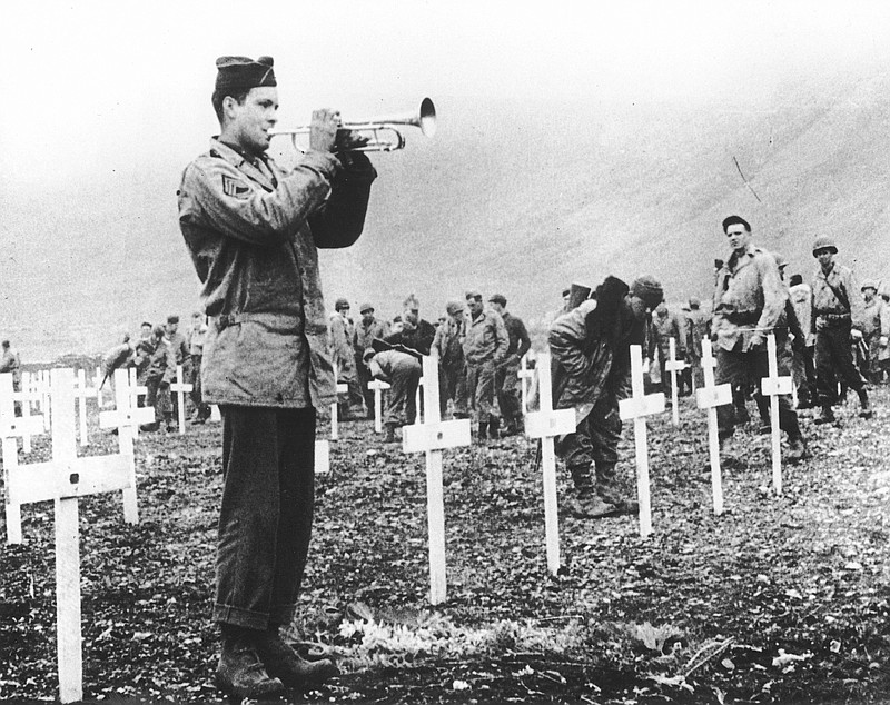 In this Aug. 1943 file photo, a bugler sounds taps during a memorial service while a group of G.I.s visit the graves of comrades who fell in the reconquest of Attu Island, part of the Aleutian Islands of Alaska. May 30, 2018 will mark the 75th anniversary of American forces recapturing Attu Island in Alaska's Aleutian chain from Japanese forces. It was the only World War II battle fought on North American soil. (AP Photo, File)