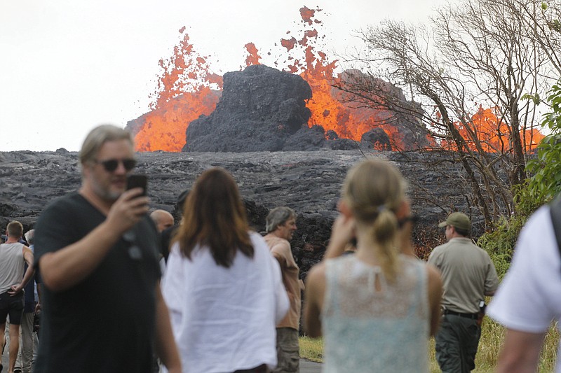 In a Saturday, May 26, 2018, photo, area residents, the media and national guard flock to what is now the end of Leilani Avenue to take in the fiery show at fissures 2, 7 and 8 of the Kilauea volcano near Pahoa. (George F. Lee/The Honolulu Advertiser via AP)