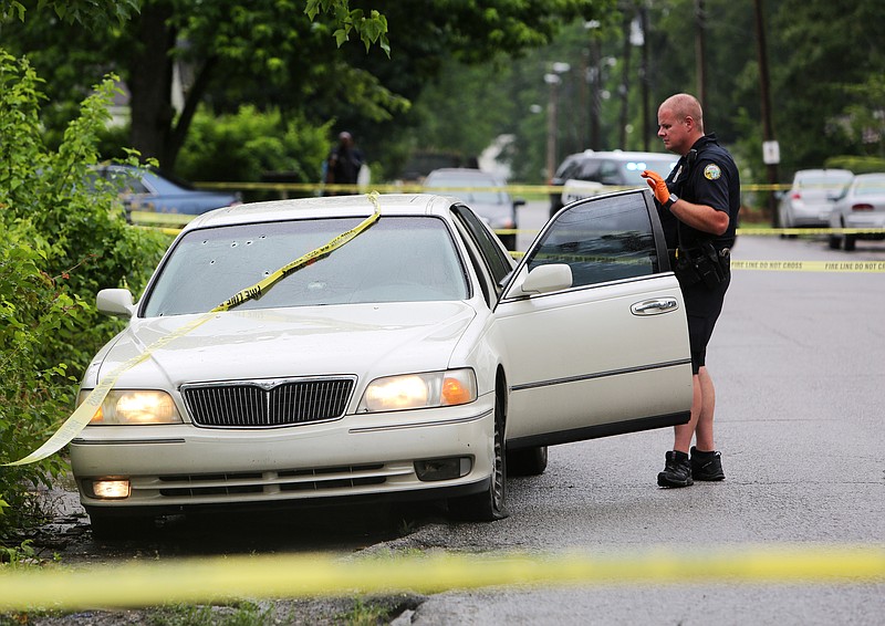 A Chattanooga Police officer checks out the inside of a car riddled with bullets in the 1600 block of South Hawthorne Street Tuesday, May 29, 2018 in Chattanooga, Tennessee. Tuesday was the latest of a string of shootings that occurred over the Memorial Day holiday weekend. 