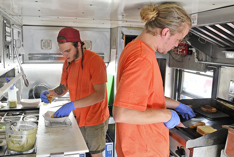 From left, Jake Stevens and Rowan Slinger work in the grilled cheese emergency! food truck at the Chattanooga Market on Sunday. The city council is considering new rules for food trucks on city property.