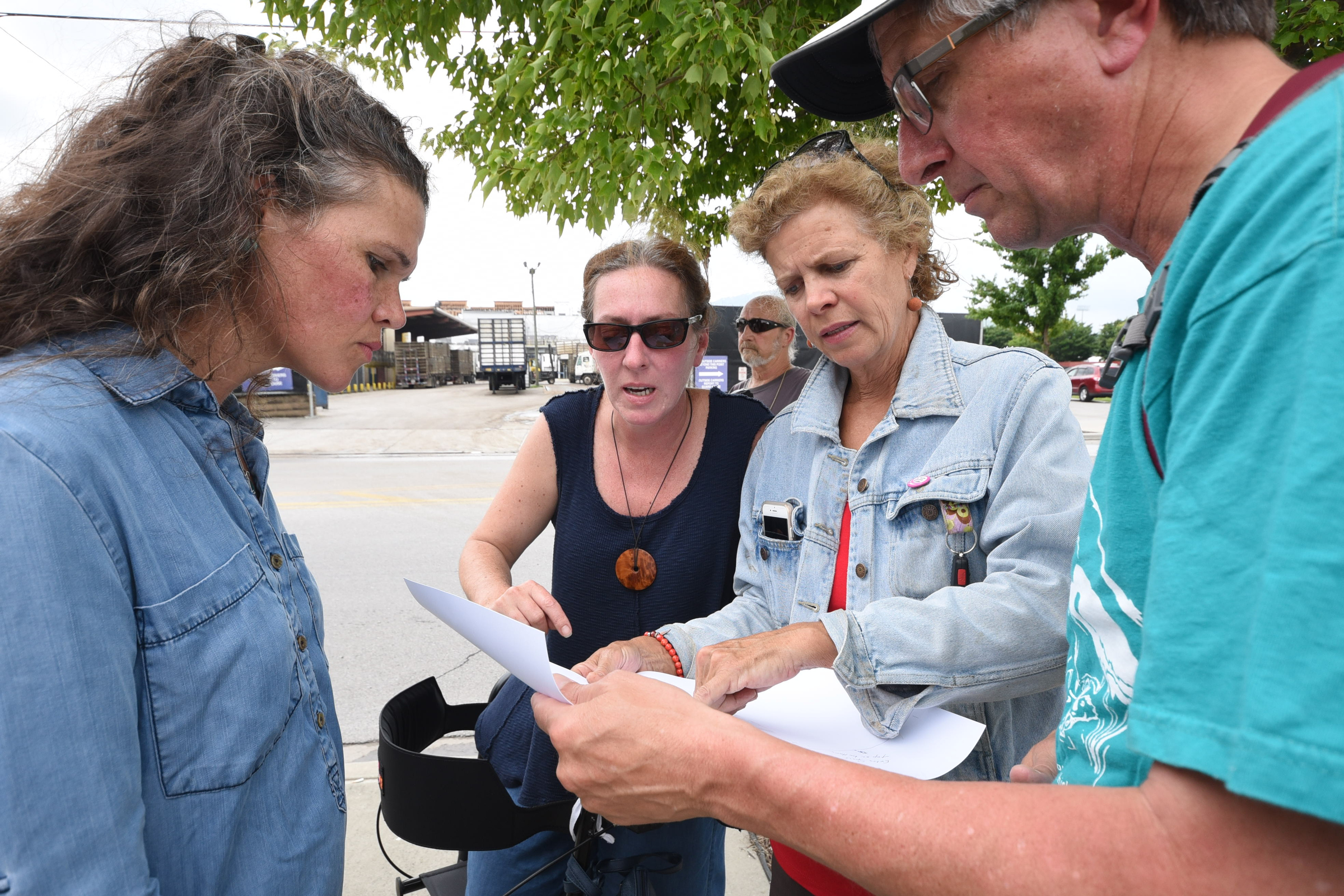 Across West Main Street from the Pilgrims Pride chicken plant in downtown Chattanooga, Ruth Almeter, left, Stephanie Everett, Lizzie Caldwell and Bruce bloom look at a Greenway Alliance map of the South Chickamauga Creek Watershed during a protest to the chicken plant possibly moving to McLemore Cove in North Georgia.