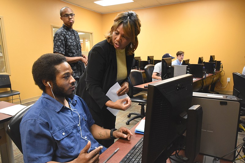 Paul Hayes receives assistance in completing his resume from Marlena Russell, director of recruiting, Thursday at the American Job Center Tennessee in Eastgate Town Center. Recruiter Travis Brewer, top left, observes the exchange.