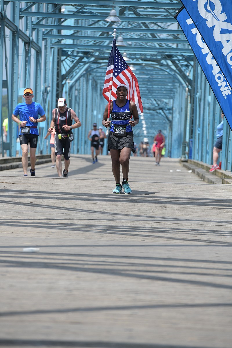 Annette Tolliver runs across the Walnut Street Bridge carrying the American flag during the recent Ironman 70.3. (Contributed photo)