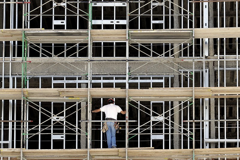 In this Friday, Oct. 6, 2017, file photo, a worker helps build an apartment and retail complex in Nashville, Tenn. The National Association for Business Economics says in its latest quarterly outlook that its panel of 45 economists expects the economy, as measured by the gross domestic product, to expand 2.8 percent this year. That is down slightly from the panel's March forecast which put GDP growth this year at 2.9 percent. (AP Photo/Mark Humphrey, File)