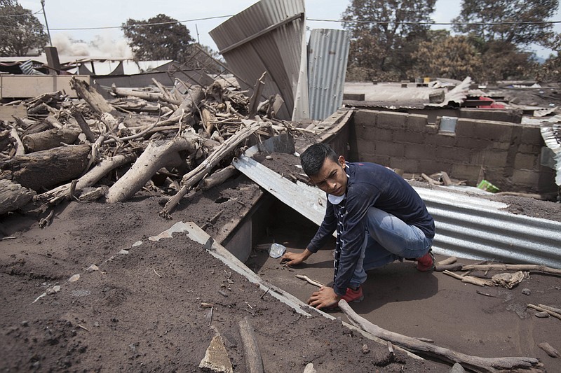 Bryan Rivera sifts through the remains of his house, after his family went missing during the Volcan de Fuego or "Volcano of Fire" eruption, in San Miguel Los Lotes, Guatemala, Thursday, June 7, 2018. Guatemala's national disaster agency suspended search and rescue efforts at the zone devastated by the eruption, saying climatic conditions and still-hot volcanic material makes it dangerous for the rescuers. (AP Photo/Moisés Castillo)