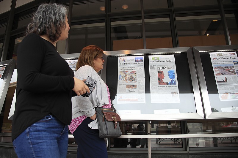 Newseum visitors browse newspaper front pages displayed outside the museum in Washington, Monday, June 11, 2018. 