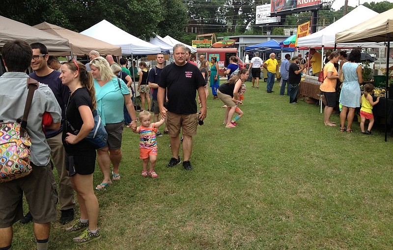 Visitors browse booths at an outdoor market.