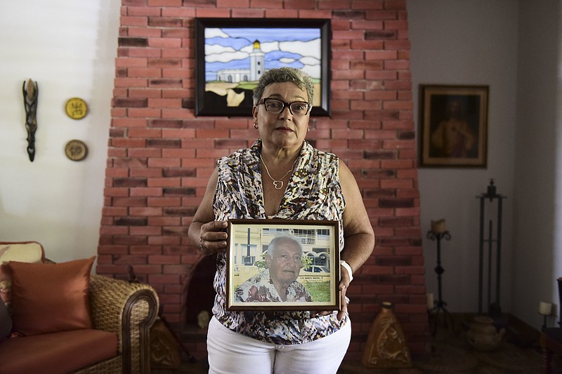 Nerybelle Perez poses with a portrait of her father, World War II veteran Efrain Perez, who died inside an ambulance after being turned away from the largest public hospital when it had no electricity or water, days after Hurricane Maria passed, in Guaynabo, Puerto Rico, Thursday, June 7, 2018.