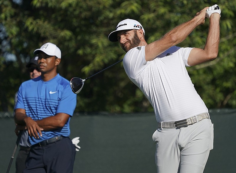 Dustin Johnson hits off the fourth tee as Tiger Woods looks on during a practice round for the U.S. Open on Tuesday at Shinnecock Hills in Southampton, N.Y.