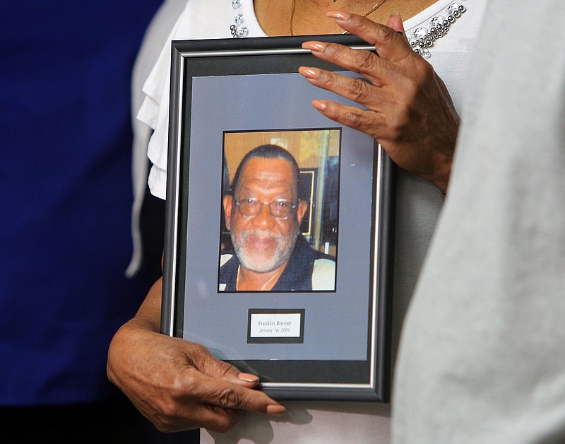 Linda Bonner holds onto a photo of her late husband Franklin Augustus Bonner during a press conference at the Newell Towers on Tuesday.