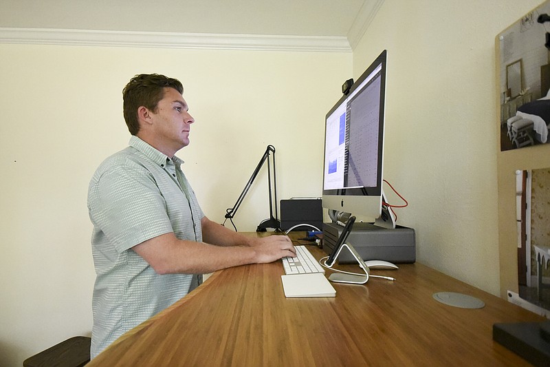 Rob Bettis stands at his desk and performs his marketing work from home in Stuart Heights.
