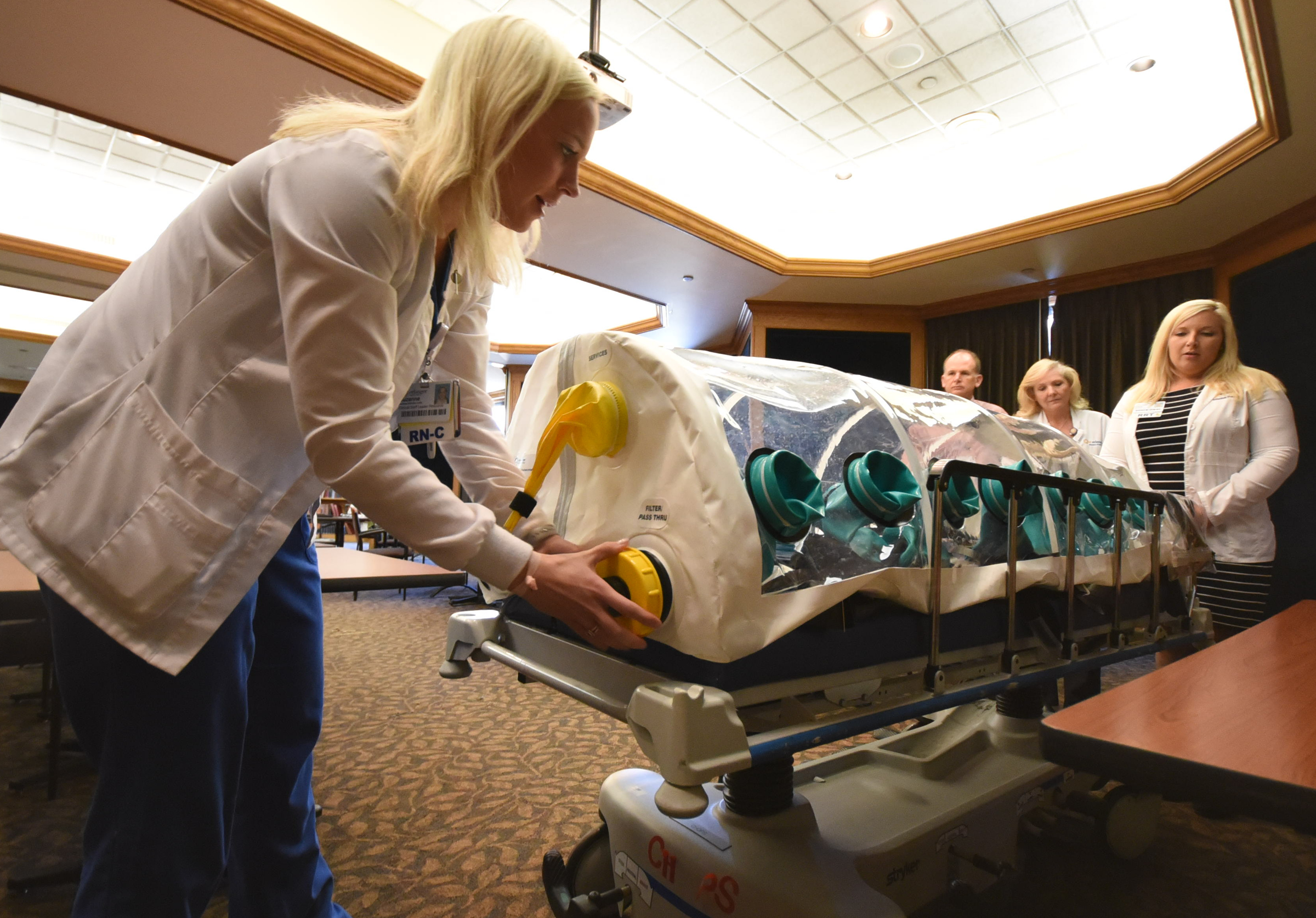 Suzanne Hornsby, left, team lead for special pathogens at Erlanger, demonstrates how critical care personnel would prepare to transport highly infectious individuals. Watching the demonstration, from left, are team members, Dr. Jay Sizemore, left, Silvia McCray and Kristy Headrick.
