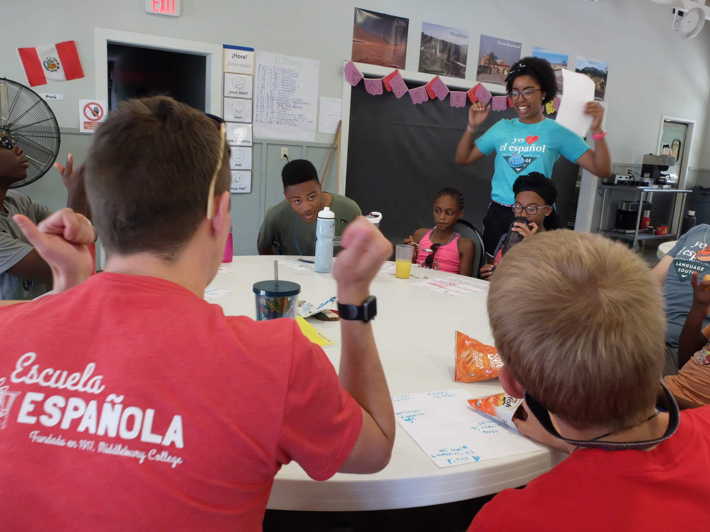 Spanish immersion camp counselor Annie Duran, top right, celebrates success for Samuel, seated left, during Aprendices 1, a learning session just before lunch at Booker T. Washington State Park.