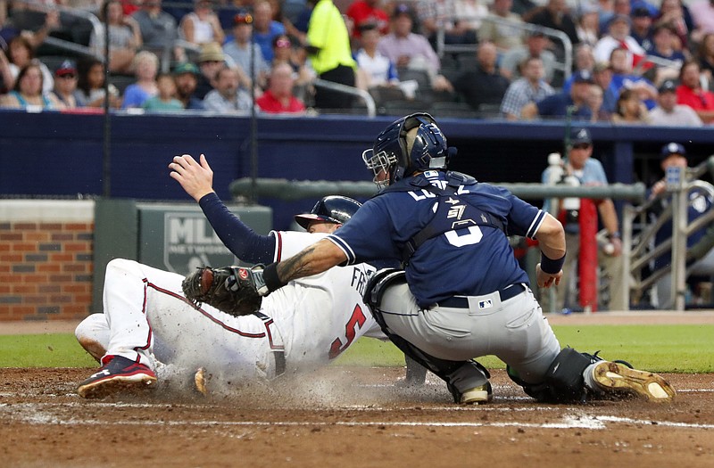 The Atlanta Braves' Freddie Freeman is tagged out by San Diego Padres catcher Raffy Lopez as he tries to score on a Kurt Suzuki grounder in the third inning of Friday night's game in Atlanta.