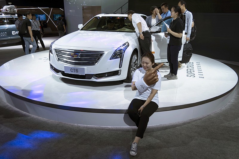 A woman poses for a photo in front of a CT6 Cadillac during the Consumer Electronics Show Asia 2018 in Shanghai, China on Friday, June 15, 2018.