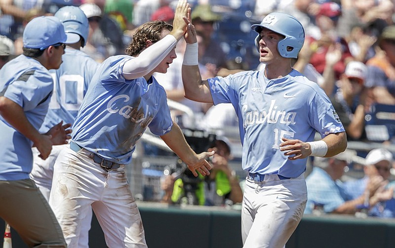 North Carolina's Michael Busch, right, is greeted by Brandon Riley after scoring on a flyout hit by Riley in the third inning of Saturday's College World Series opener against Oregon State in Omaha, Neb. North Carolina won 8-6 in a game that lasted 4 hours, 24 minutes, setting the record for a nine-inning contest at the CWS.