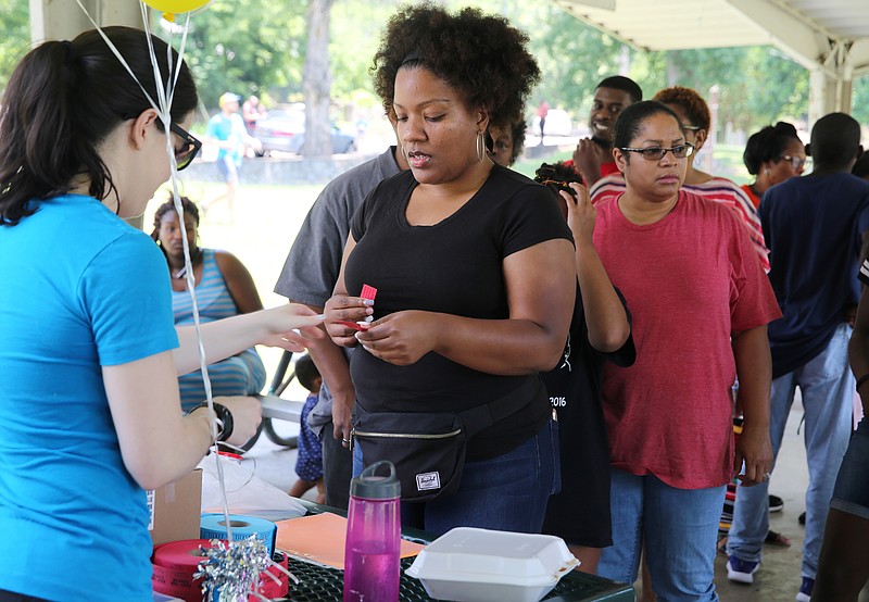 Mary Smith hands Lasheda Little a raffle ticket Sunday, June 17, 2018 during a Tech Goes Home celebration at East Lake Park in Chattanooga, Tennessee. Little is a graduate of two Tech Goes Home courses. 