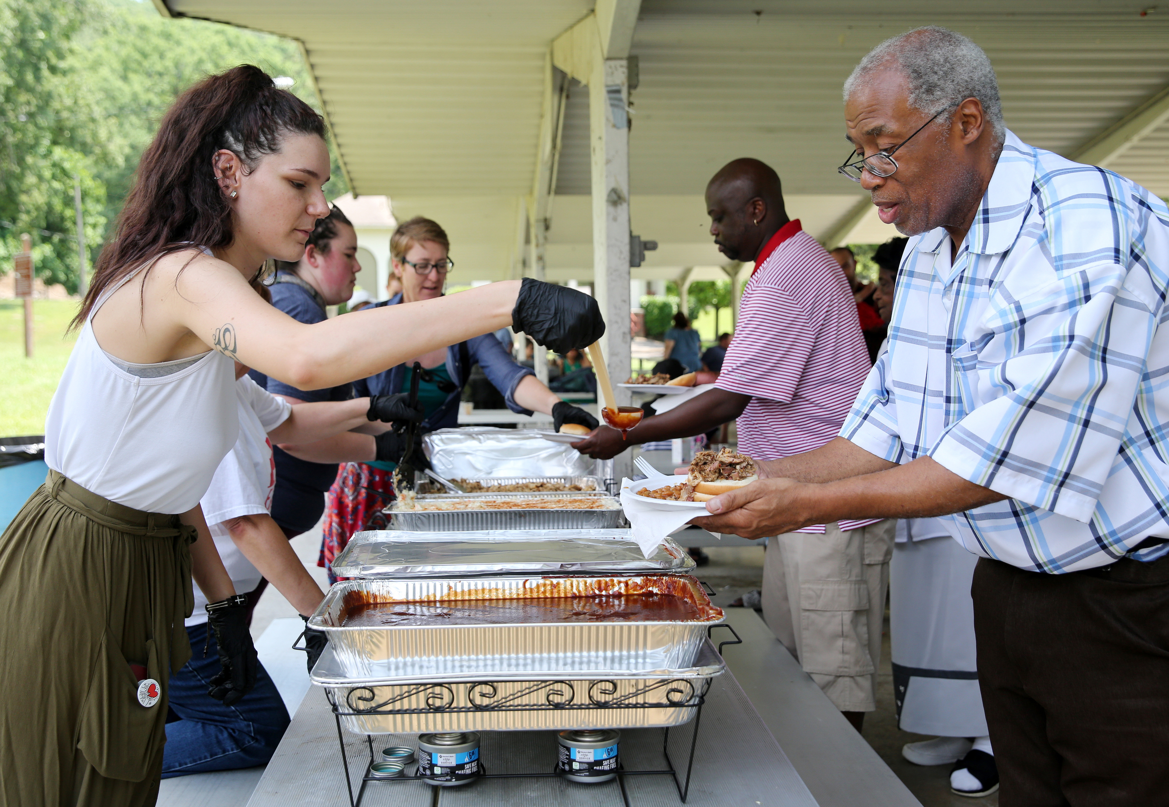 Alyssa Williams give Roy Allison barbecue sauce during a Tech Goes Home celebration Sunday, June 17, 2018 at East Lake Park in Chattanooga, Tennessee. Allison was 2015 a graduate of the program.
