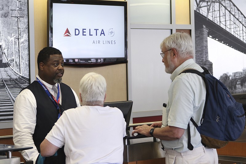 Staff file photo / Delta associate Sheldon Posey, left, talks to a couple of passengers at Chattanooga Metropolitan Airport. Delta plans to start offering nonstops to New York City in July.