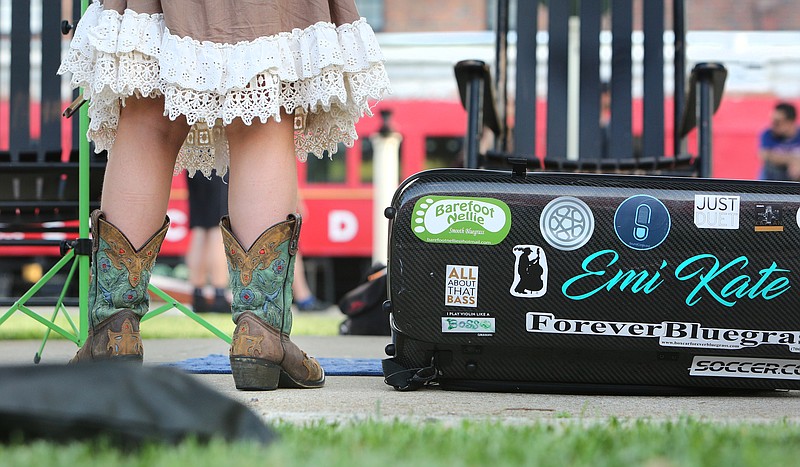 Emi Riemer, 8, stands by her fiddle case as she busks at the Chattanooga Choo Choo Gardens. Emi started playing fiddle and singing when she was 6. She befriended singer/songwriter EmiSunshine and wears boots once worn by her hero on the Grand Ole Opry stage.