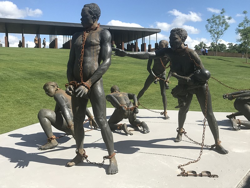 A bronze sculpture on the grounds of the National Memorial for Peace and Justice shows several figures in chains.