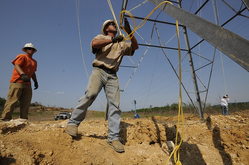 Staff file photo by Tim Barber/ Workers uncoil a line at the base of a TVA transmission tower before pulling new high-tension power lines near the Widows Creek Coal plant in Stevenson, Ala.